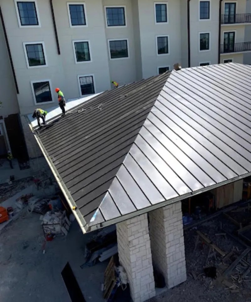 Crew installing standing seam metal roof panels on a commercial project in Searcy
